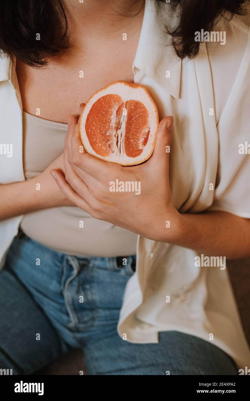 Colpo verticale di una donna che tiene un taglio arancione sopra la sua che Foto Stock