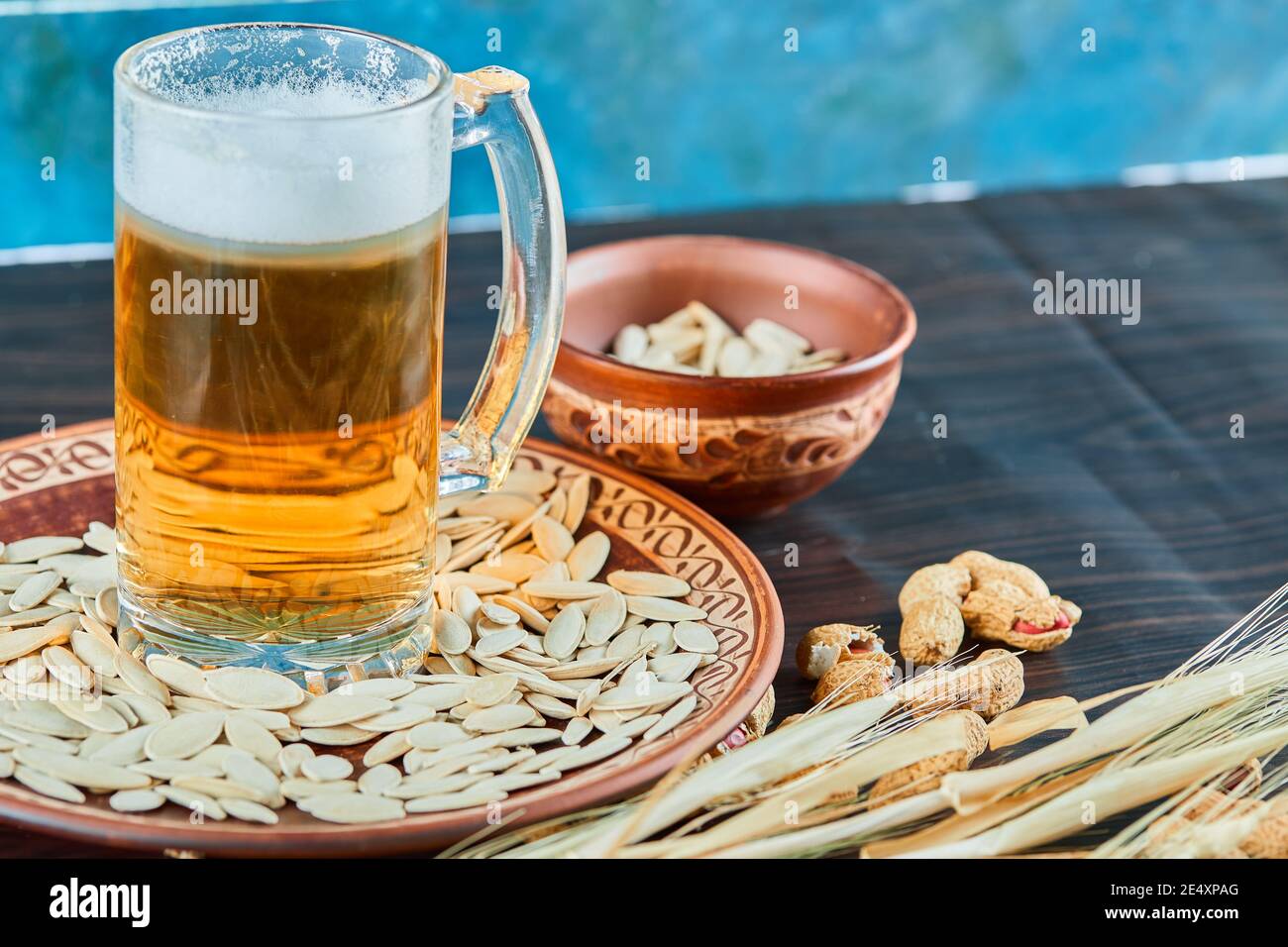 Semi di fiori di sole, arachidi e un bicchiere di birra su un tavolo scuro Foto Stock