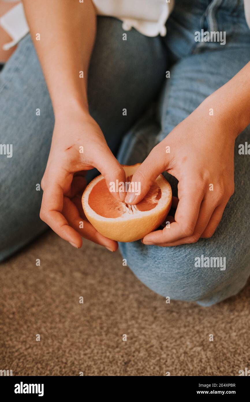 Mani di messa a fuoco poco profonde che tengono un taglio arancione Foto Stock