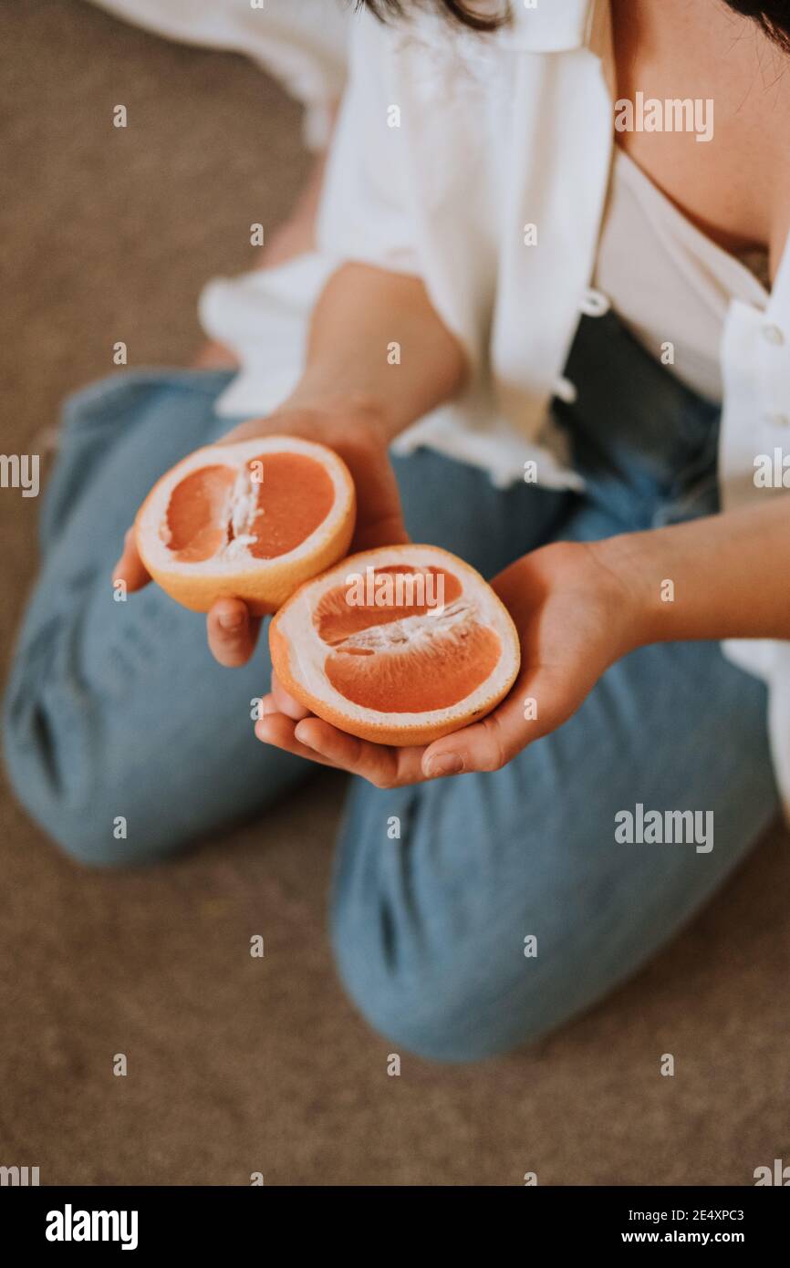 Messa a fuoco poco profonda di una donna che tiene a metà taglio arance Foto Stock