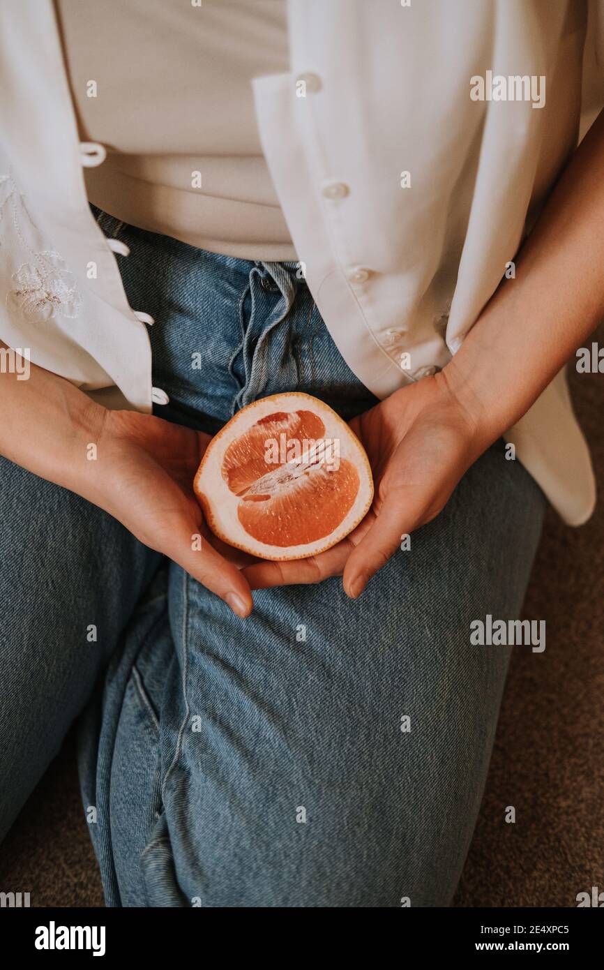Colpo di primo piano di una donna che tiene in mano un'arancia tagliata le mani Foto Stock