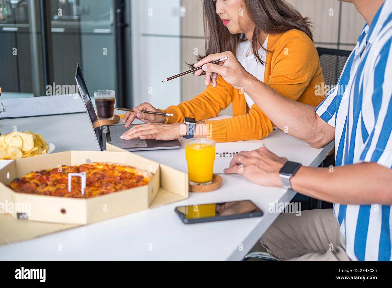Amici che parlano e mangiano la pizza nella sala riunioni. Foto Stock