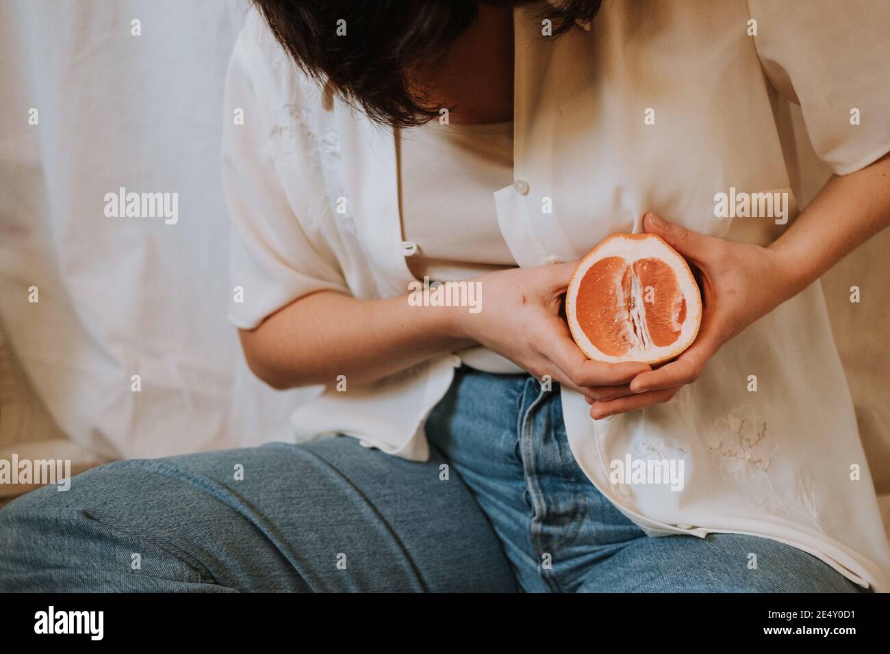 Colpo di primo piano di una donna che tiene un taglio arancione sopra il suo petto Foto Stock