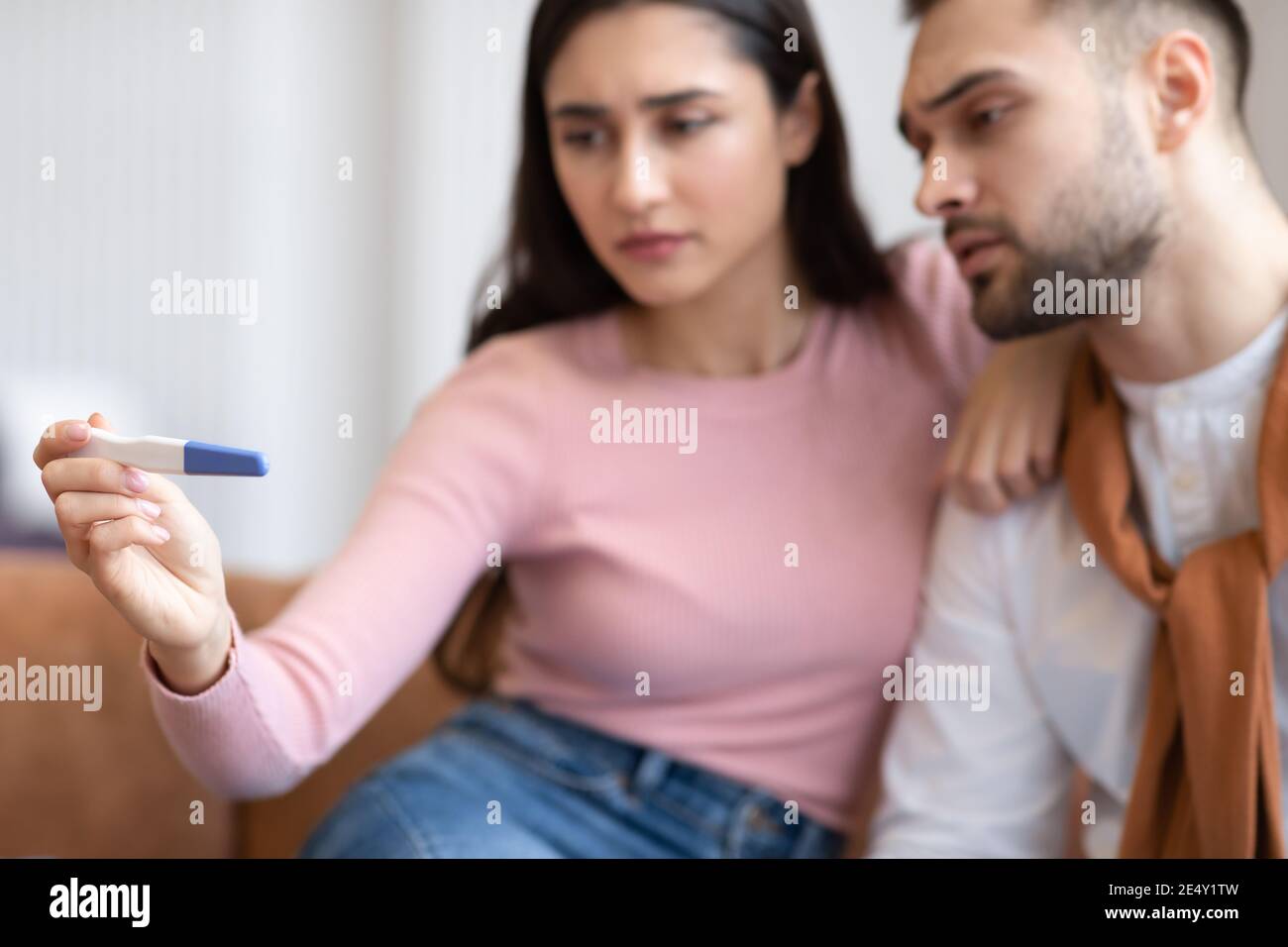 La coppia araba depressa tiene un test di gravidanza negativo seduto a casa Foto Stock