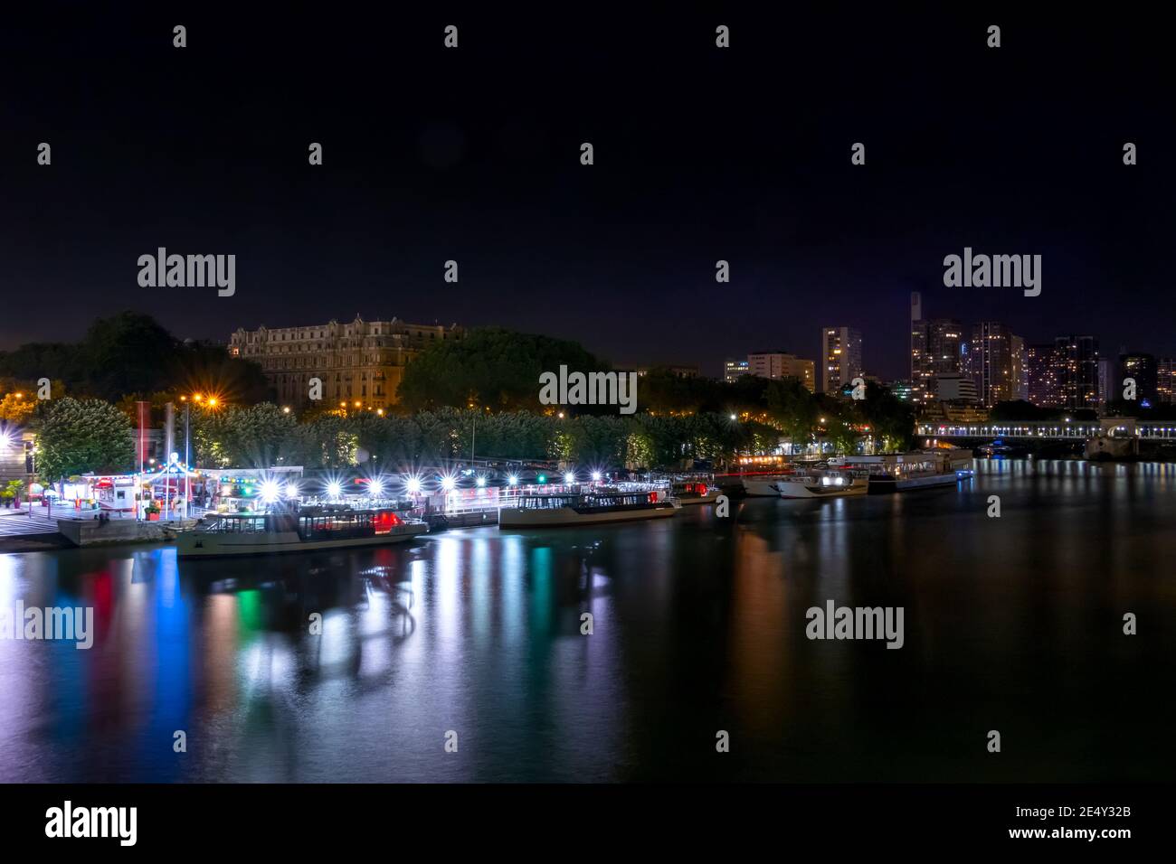Francia. Notte estiva a Parigi. Le navi da diporto sono ormeggiate al lungofiume della Senna. Molte luci multicolore Foto Stock