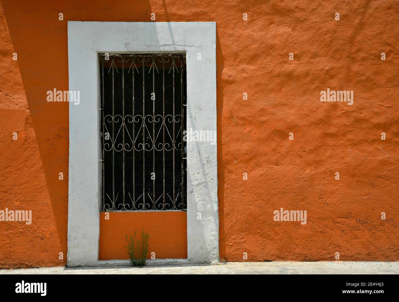 Facciata casa coloniale con una parete in stucco veneziano e una finestra con griglie in ferro artigianali ad Atlixco, Puebla Messico. Foto Stock