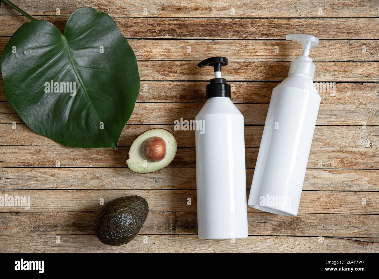 Still life con bottiglie bianche mock-up con dispenser e avocado. Cosmetici biologici e concetto di bellezza. Foto Stock