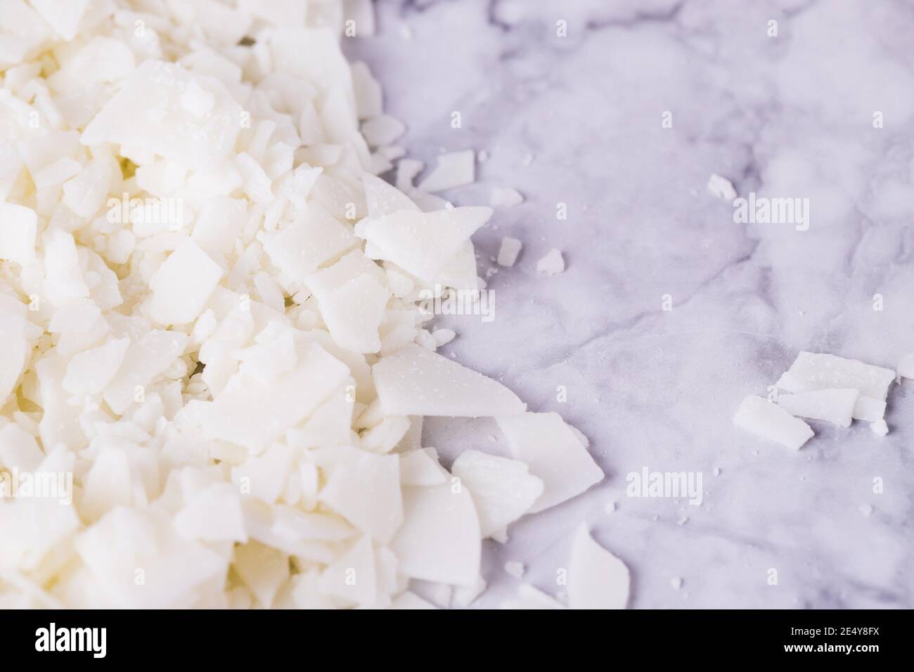 Fiocchi bianchi di cera di soia per la produzione di candela su una luce sfondo in marmo grigio Foto Stock