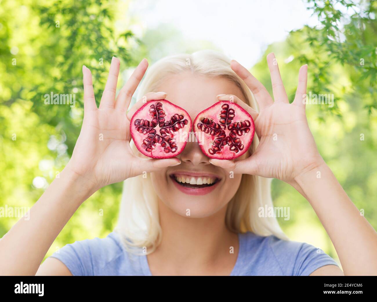 Donna felice che coprono gli occhi con melograno Foto Stock