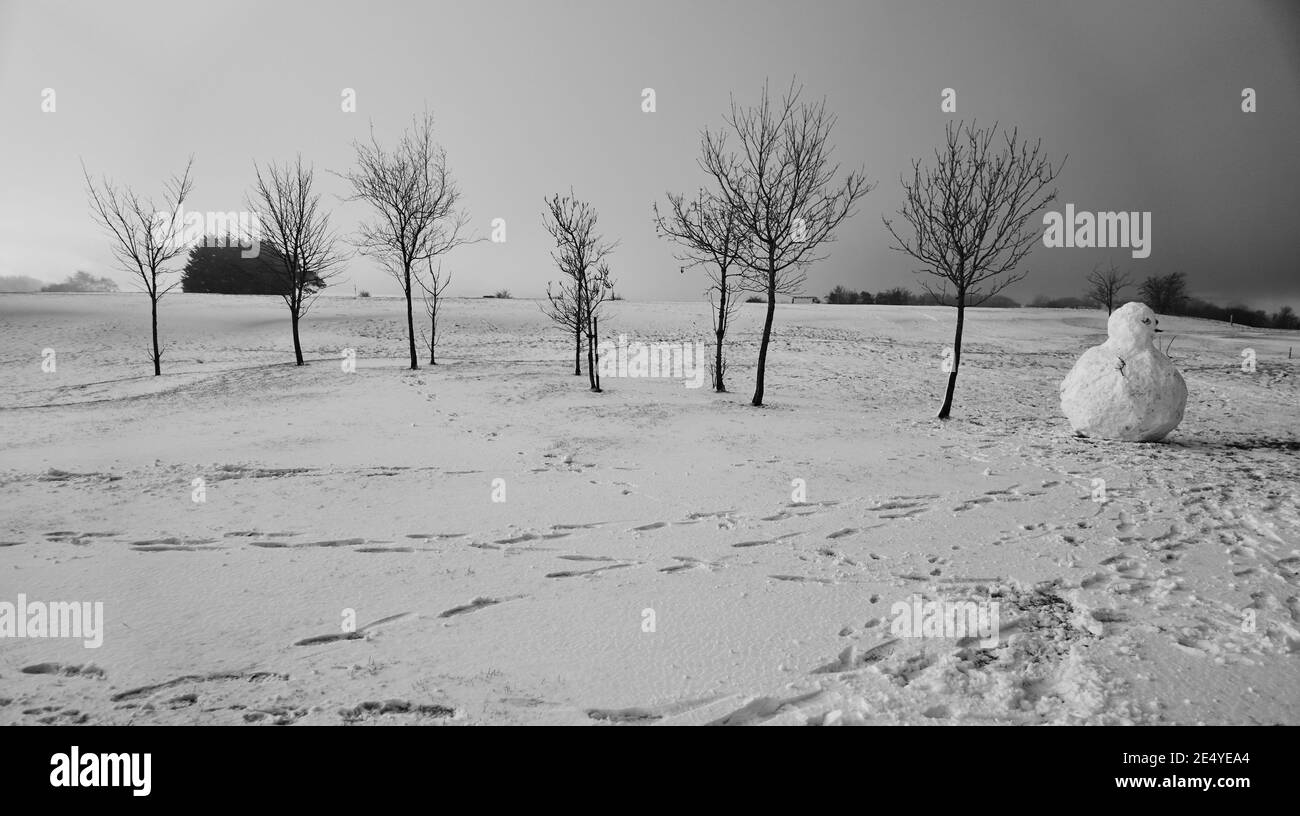 Un freddo gennaio Domenica mattina alta sul Cotswolds in Gloucestershire, Inghilterra, dopo la notte nevicata, con il Sole cercando di fare un aspetto Foto Stock