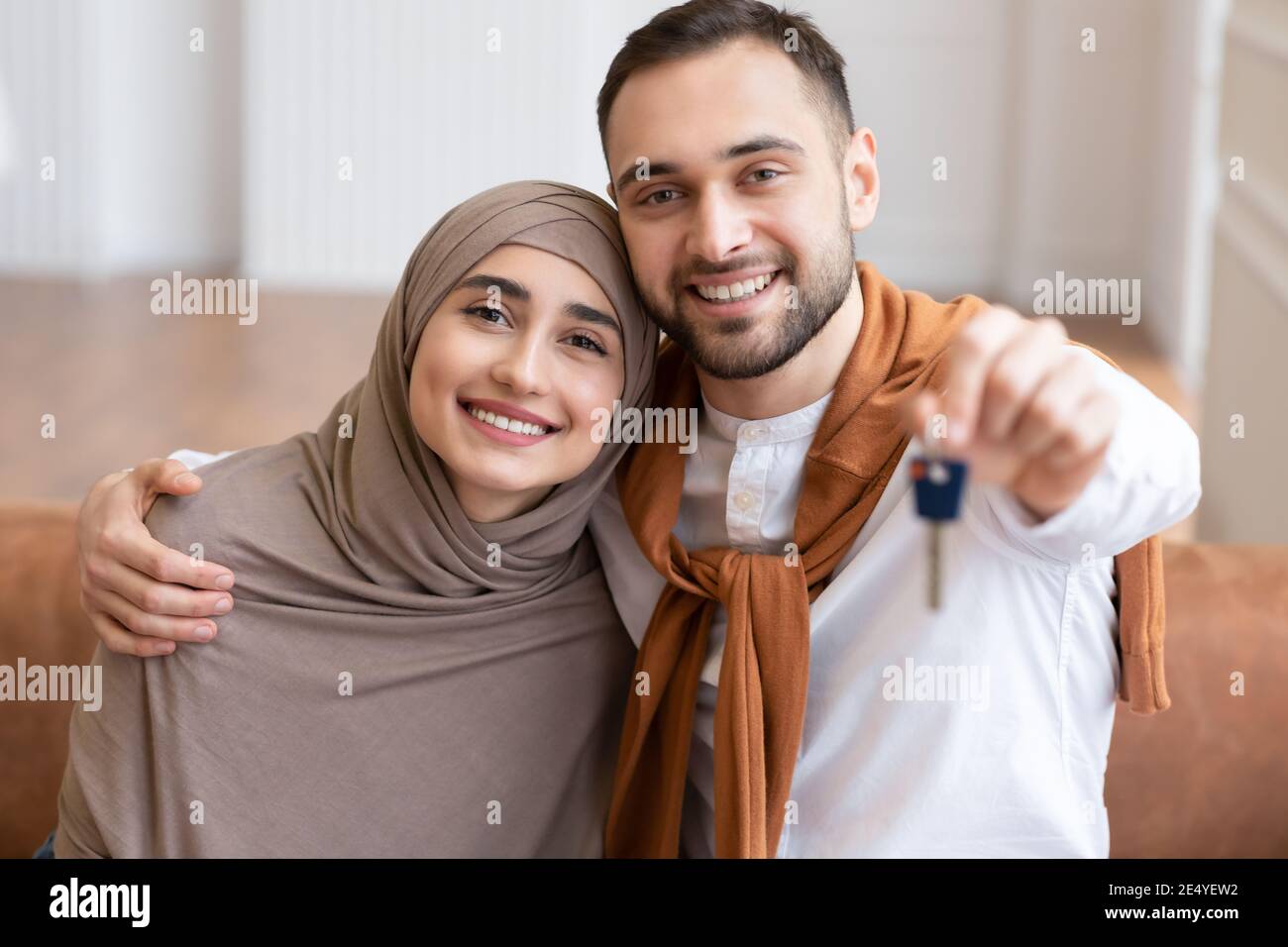 Felice famiglia musulmana coppia mostrando New House chiave seduta al chiuso Foto Stock