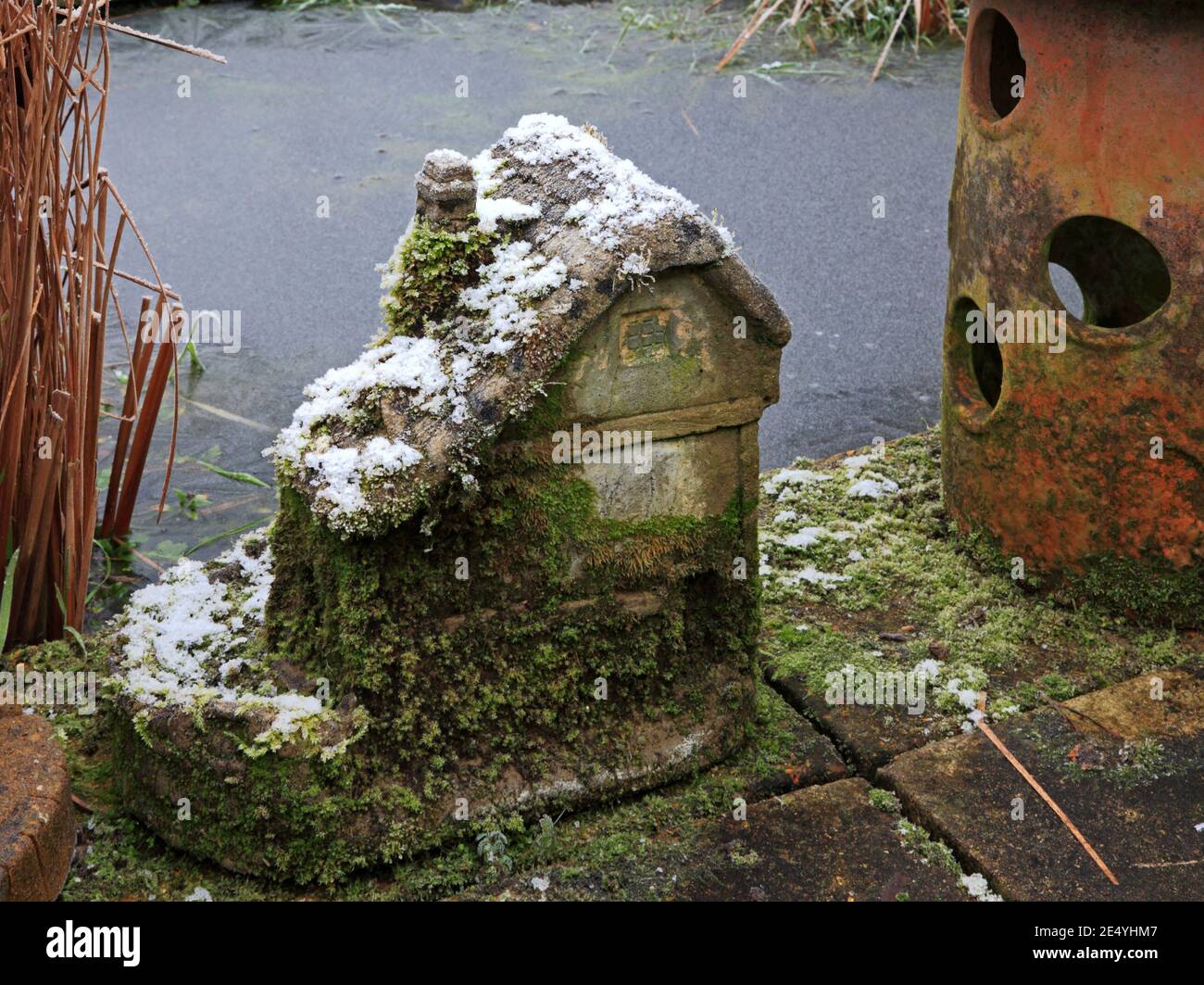 Un ornamento modellato giardino di un mulino ad acqua da un laghetto congelato in inverno a Hellesdon, Norfolk, Inghilterra, Regno Unito. Foto Stock