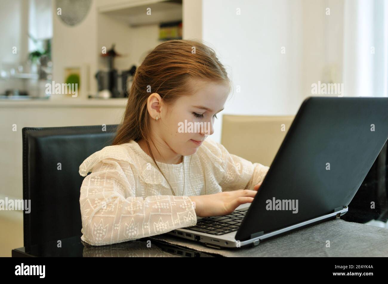 Bianca europea (caucasica) ragazza (bambino, capretto) seduto (seduto) davanti al computer e digitando. Online School, situazione pandemica. Foto Stock