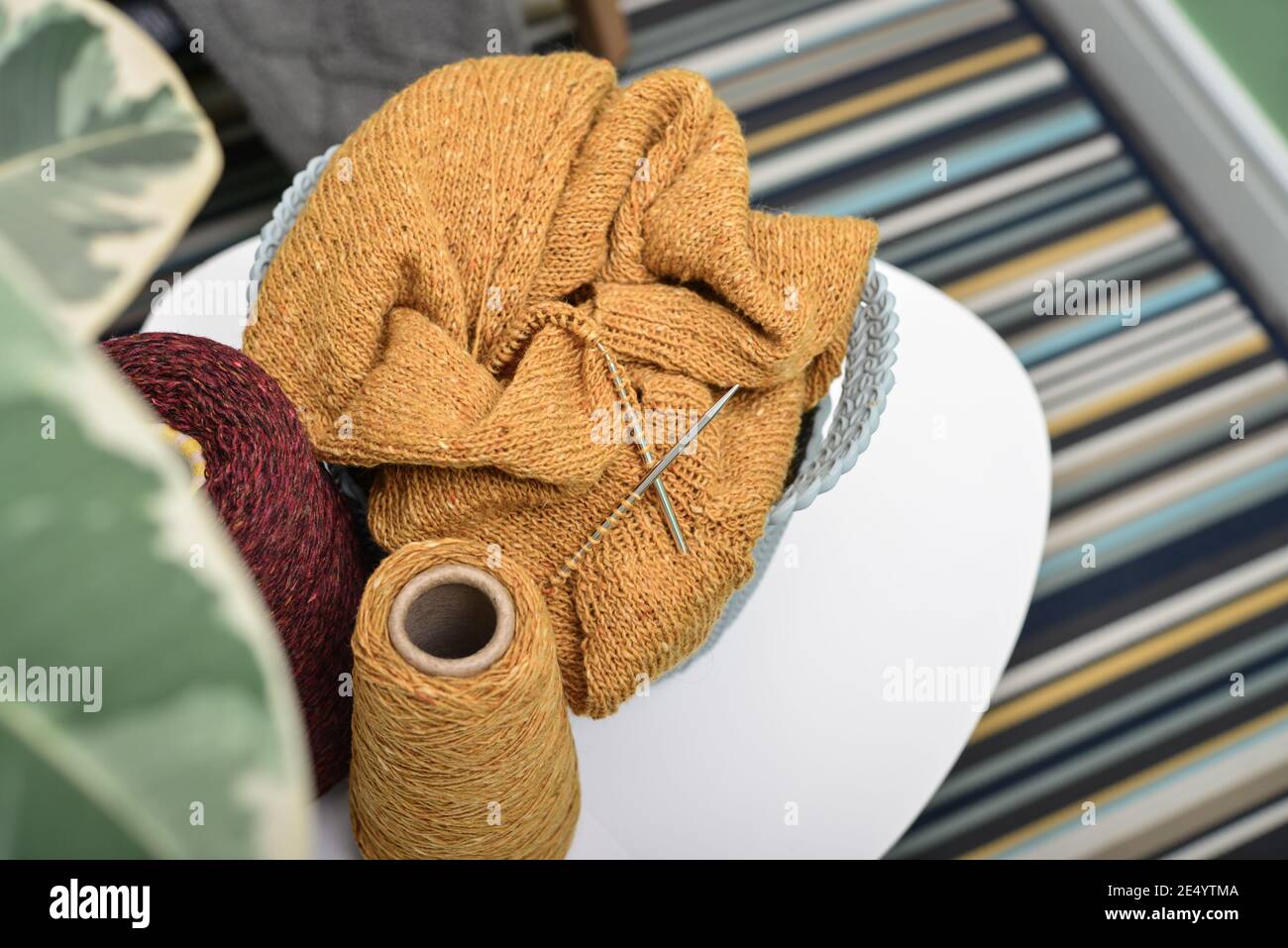 Cesto con progetto di lavorazione a maglia in corso e filato sul caffè tavolo in primo piano per interni domestici Foto Stock
