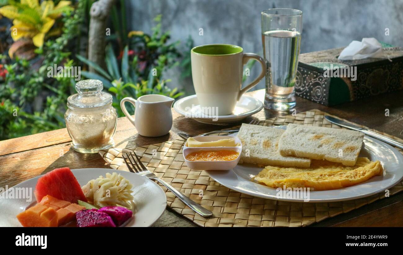 Colazione turistica tradizionale a Bali: Toast, uova strapazzate, caffè e frutta fresca Foto Stock
