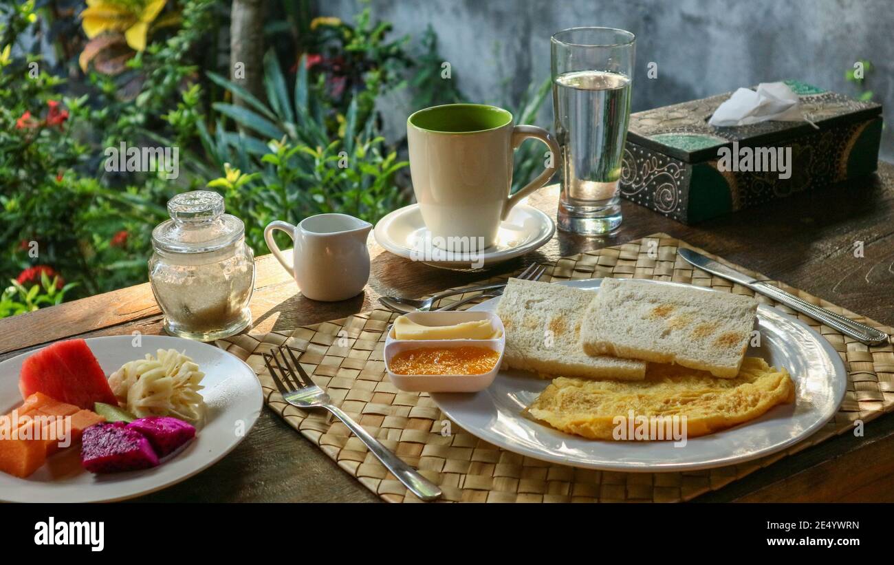 Colazione turistica tradizionale a Bali: Toast, uova strapazzate, caffè e frutta fresca Foto Stock