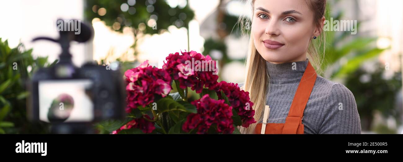 Bel giovane fiorista sorridente in negozio di fiori Foto Stock