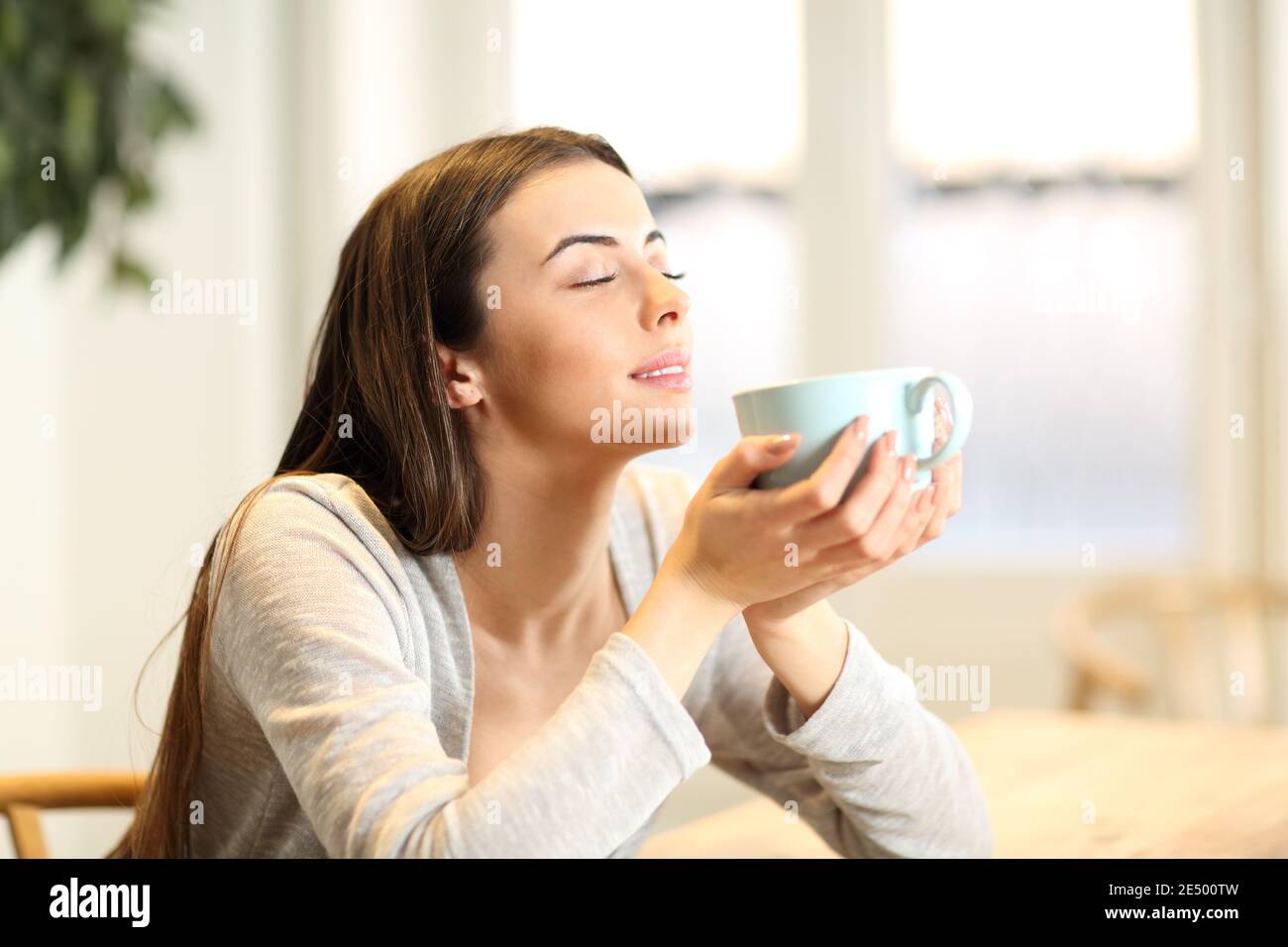 Donna felice odore caffè aroma seduta in un tavolo a. casa Foto Stock