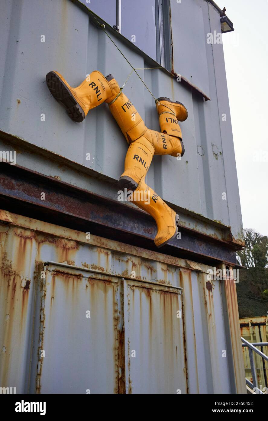 Tre gambe di uomo realizzate con stivali wellington gialli RNLI a Douglas, Isola di Man Foto Stock