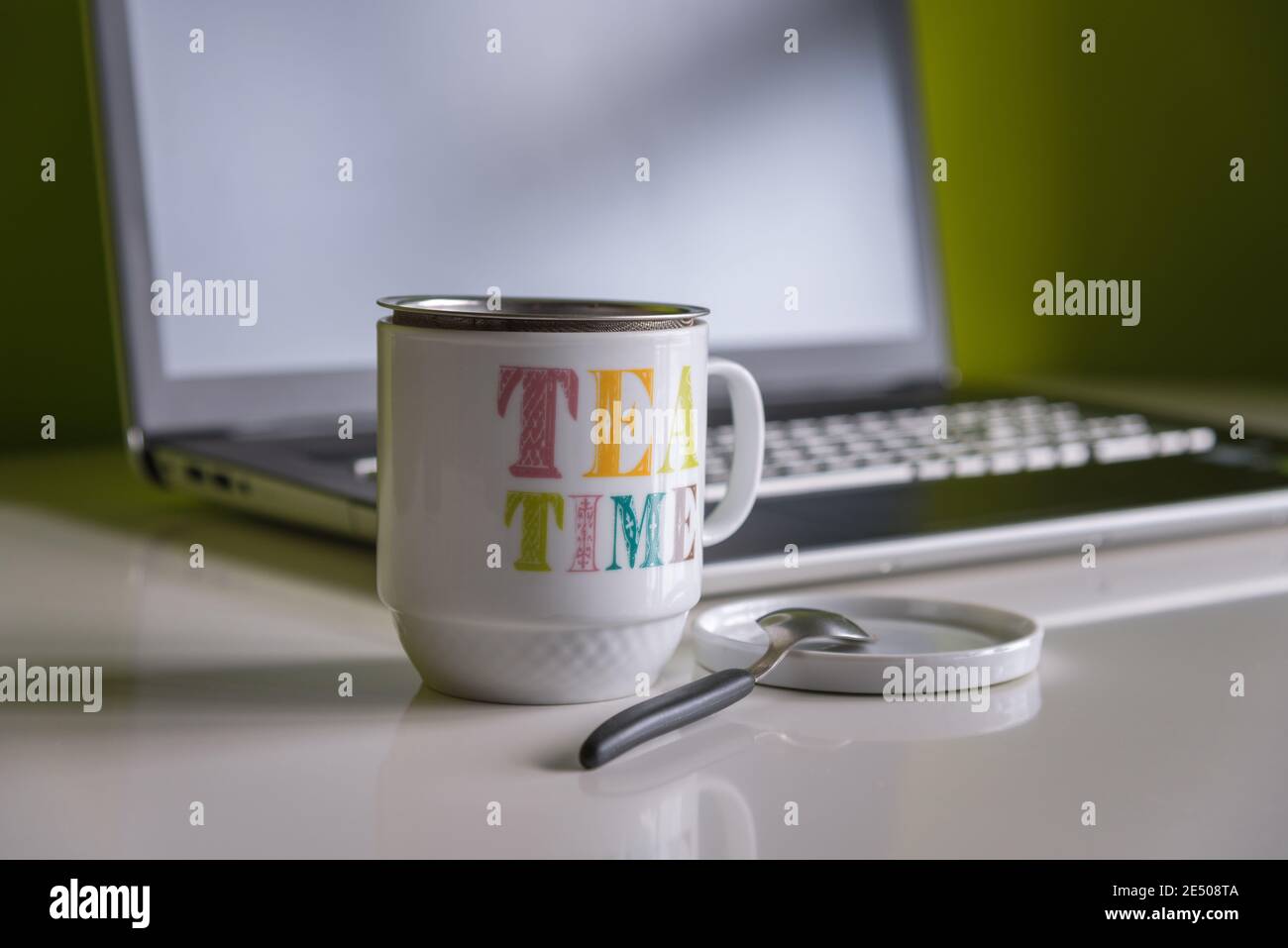 Rilassante tempo per il tè lavorando in remoto a casa con un computer portatile sullo sfondo Foto Stock