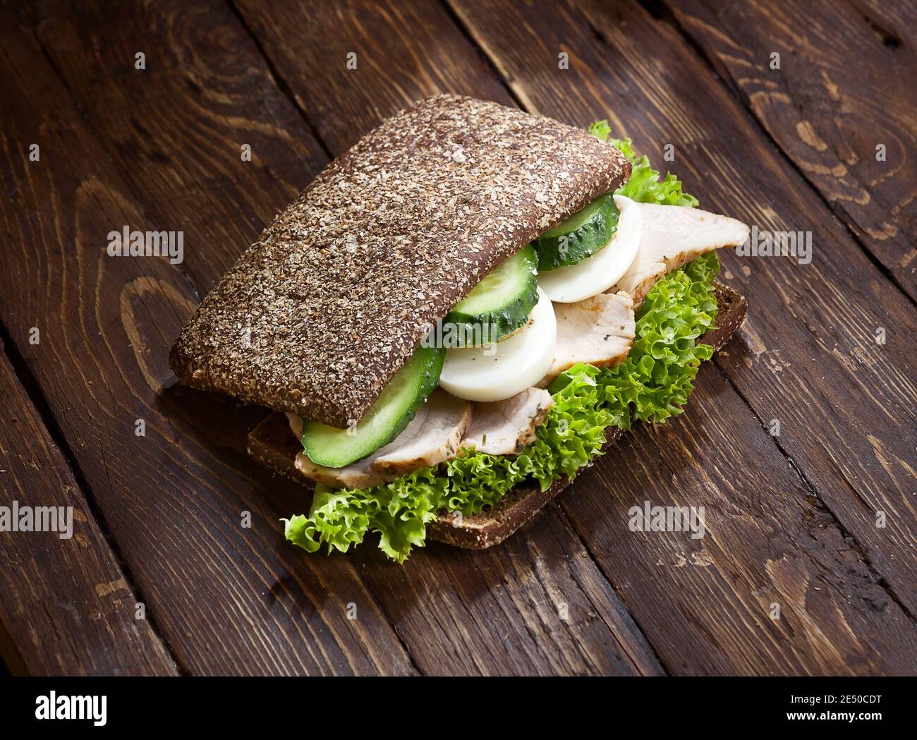 chiocciotto di tacchino sandwich con foglie di lattuga verde, uova tritate, cetrioli e pane di segala o di grano, su sfondo di legno scuro rustico tavolo, nessuno Foto Stock