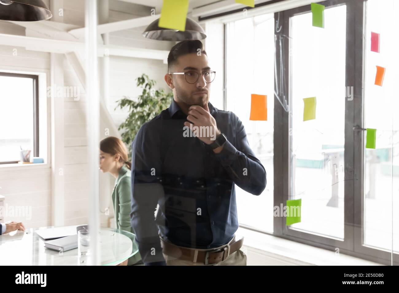 Uomo d'affari arabo pensieroso che indossa gli occhiali che guardano le carte appiccicose Foto Stock