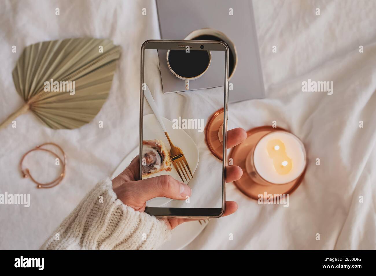 Donna mano che scattano foto della composizione con la cottura alla cannella, il caffè e la candela che brucia Foto Stock