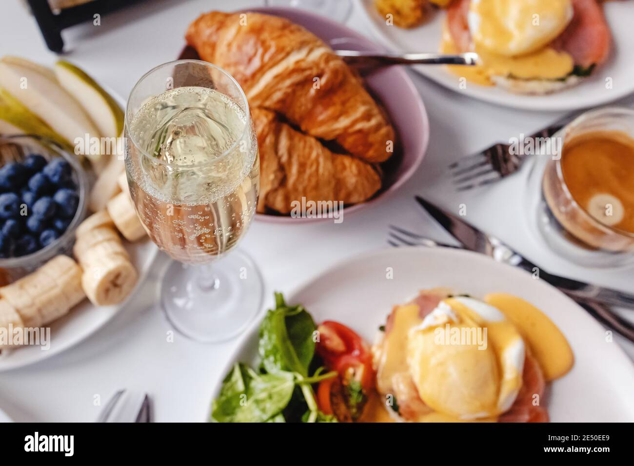 Bicchiere di champagne da vicino sul tavolo con colazione diversa e piatti del brunch Foto Stock