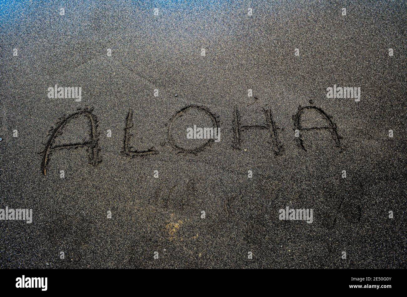Parola Aloha ha scritto su una spiaggia di sabbia nera, Big Island Hawaii Foto Stock