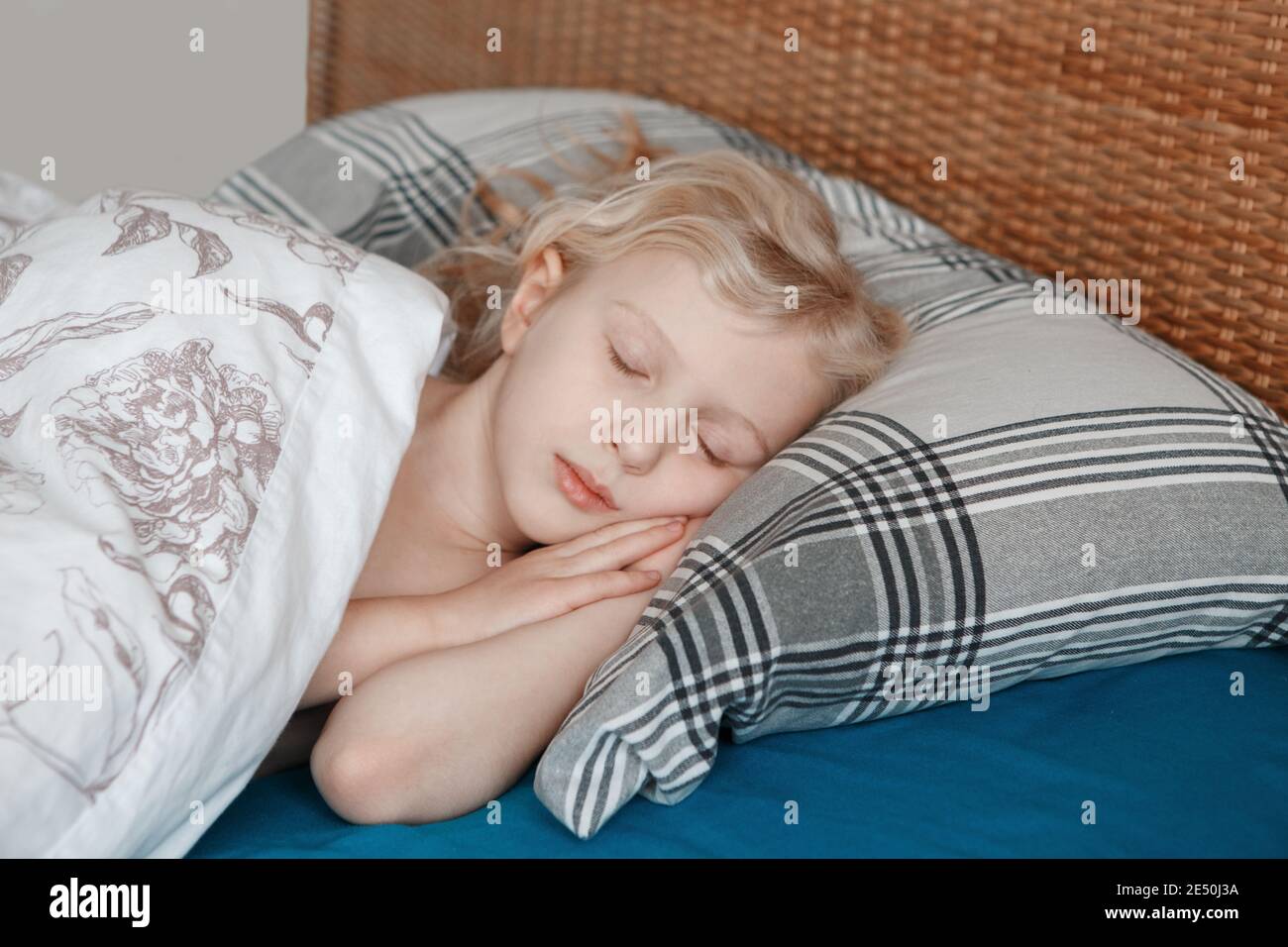 Carino adorabile bambina bionda caucasica che dorme sul cuscino nel letto a casa. Sogni dolci e vibrazioni del letto. Routine quotidiana di mattina presto. Foto Stock