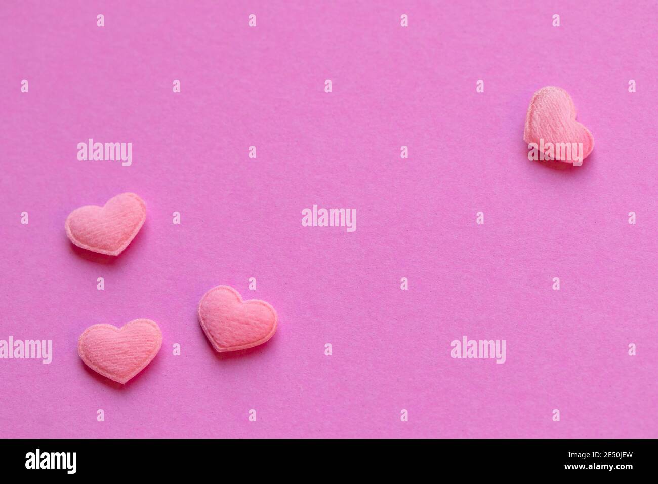 Un sacco di cuori piccoli rosa sono allineati sullo sfondo di carta rosa. Concetto di San Valentino con spazio di copia per il testo. Foto Stock