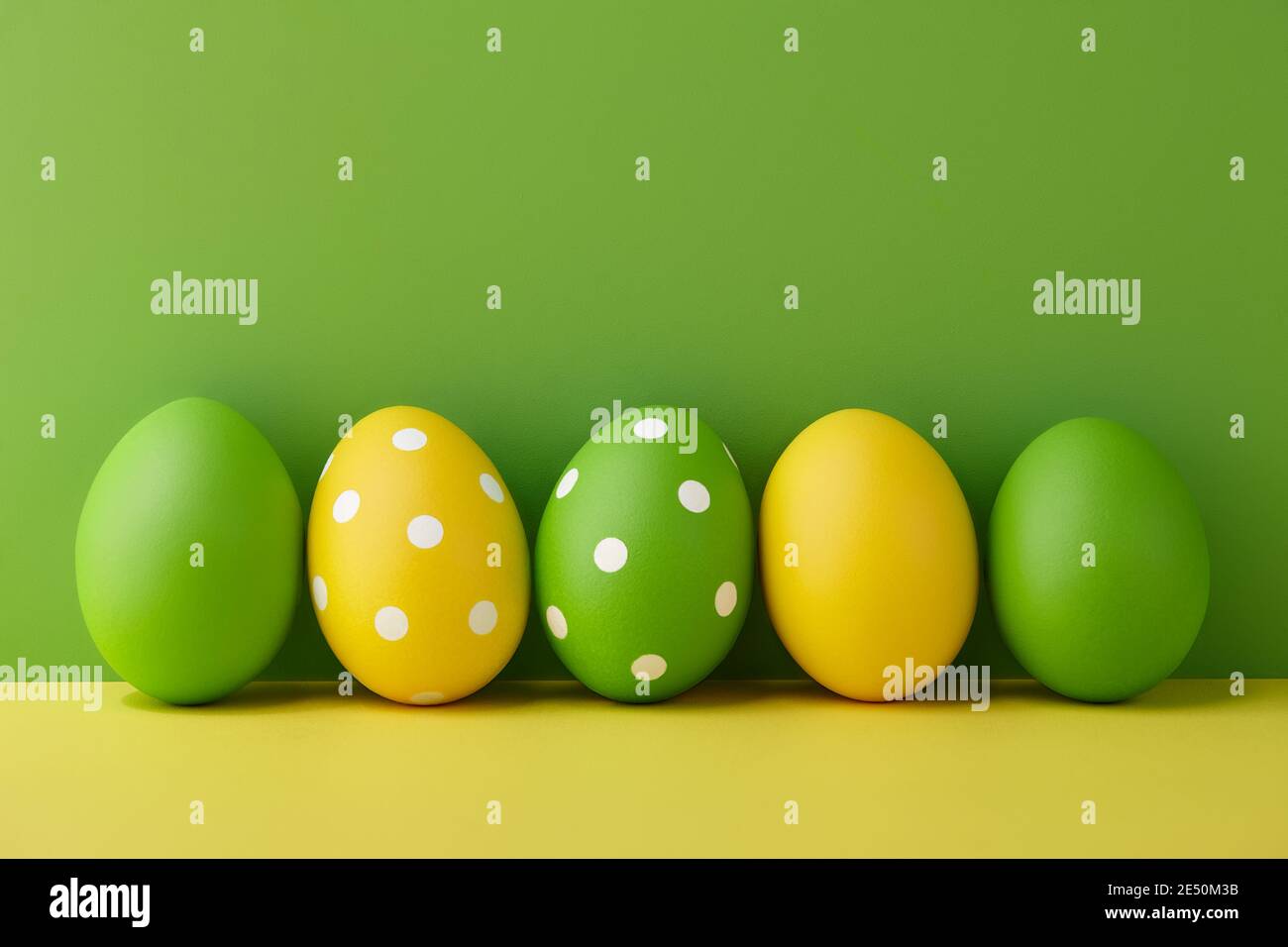 Uova di Pasqua dipinte su sfondo verde e giallo, preparazione delle vacanze primaverili Foto Stock