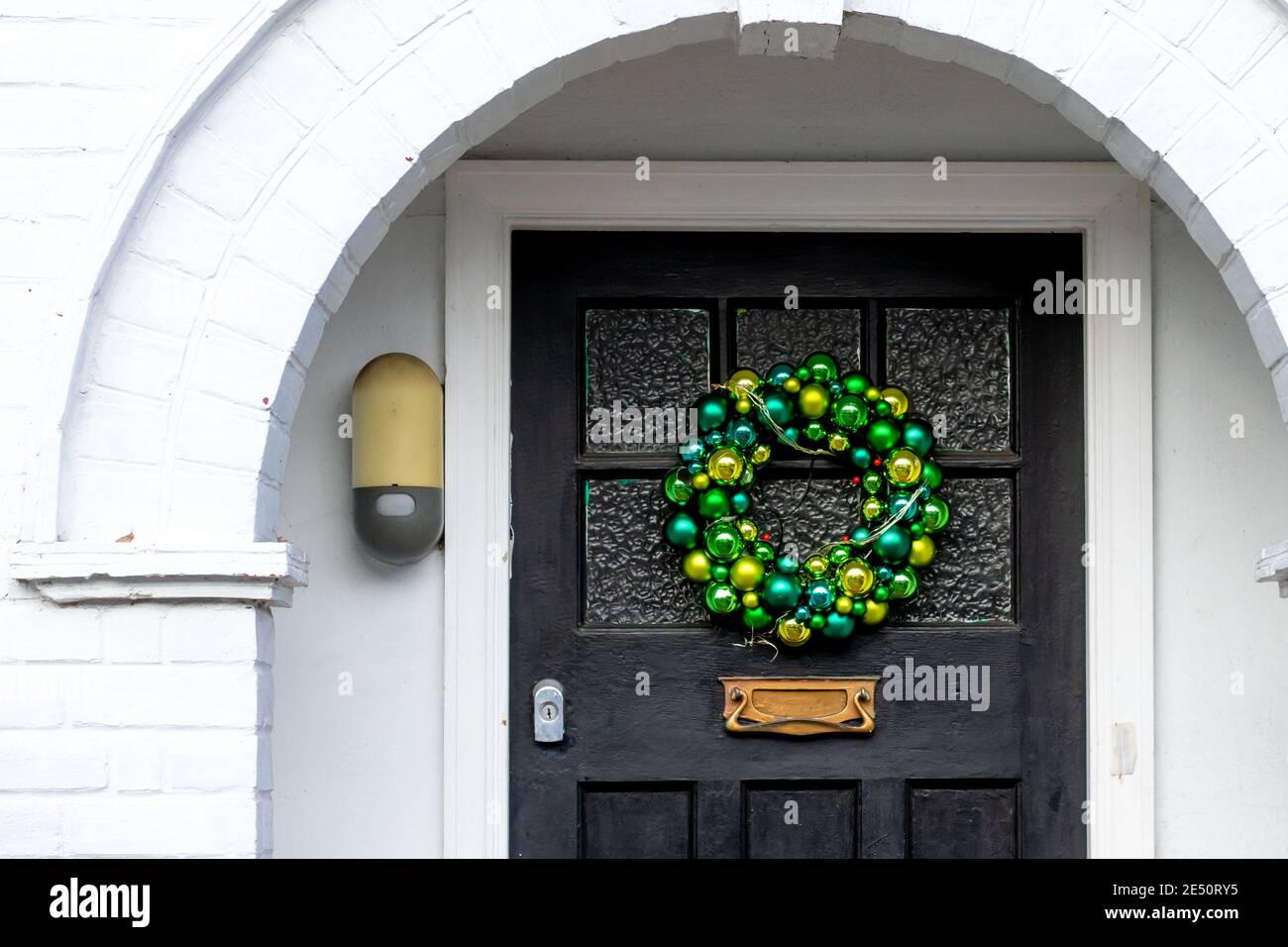 I baubles verdi formano una corona di Natale su una porta anteriore sotto un alcova Foto Stock