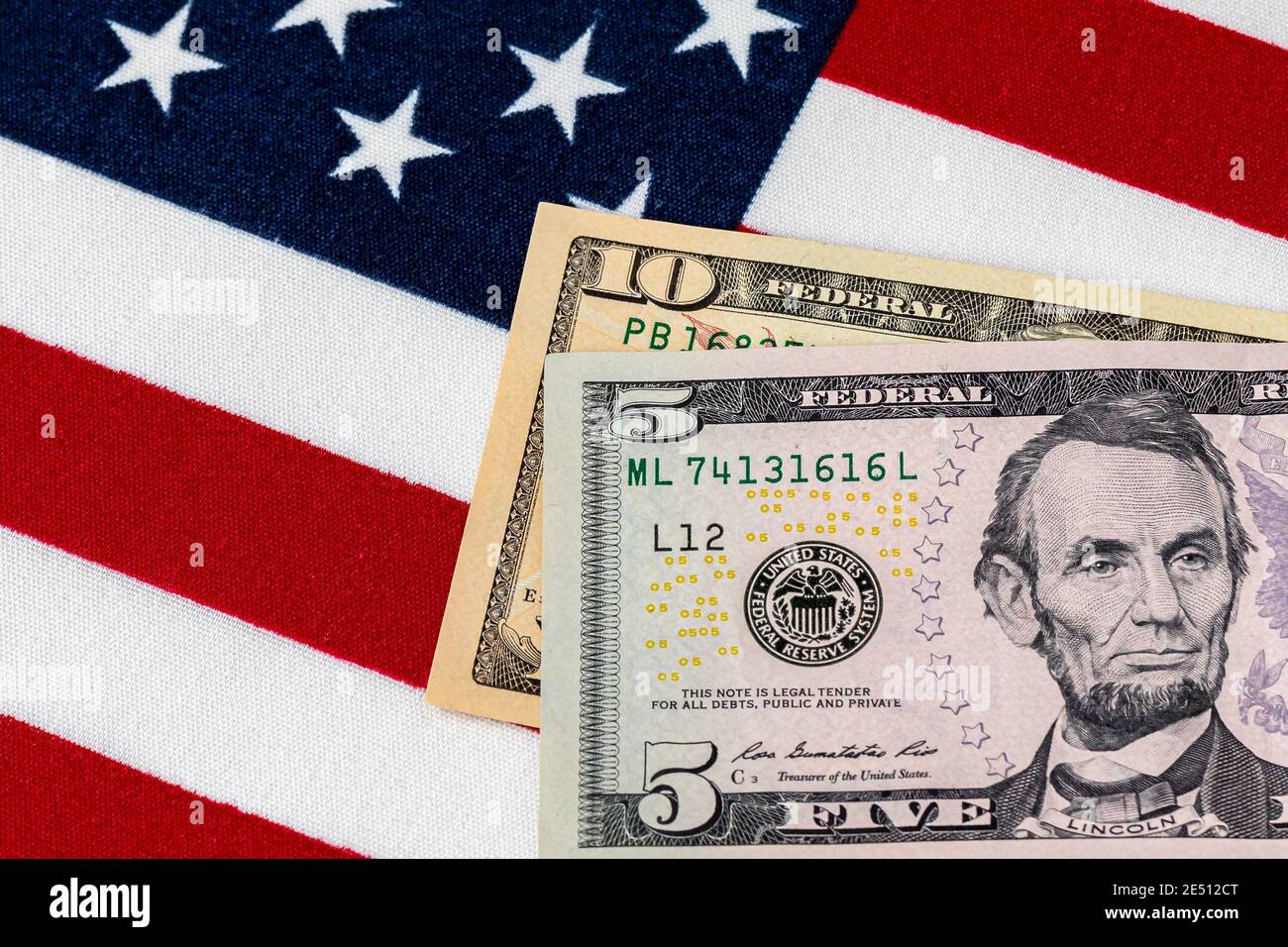 Closeup di dieci e cinque dollari fatture con bandiera americana. Concetto di aumento minimo salariale federale di 15 dollari. Foto Stock