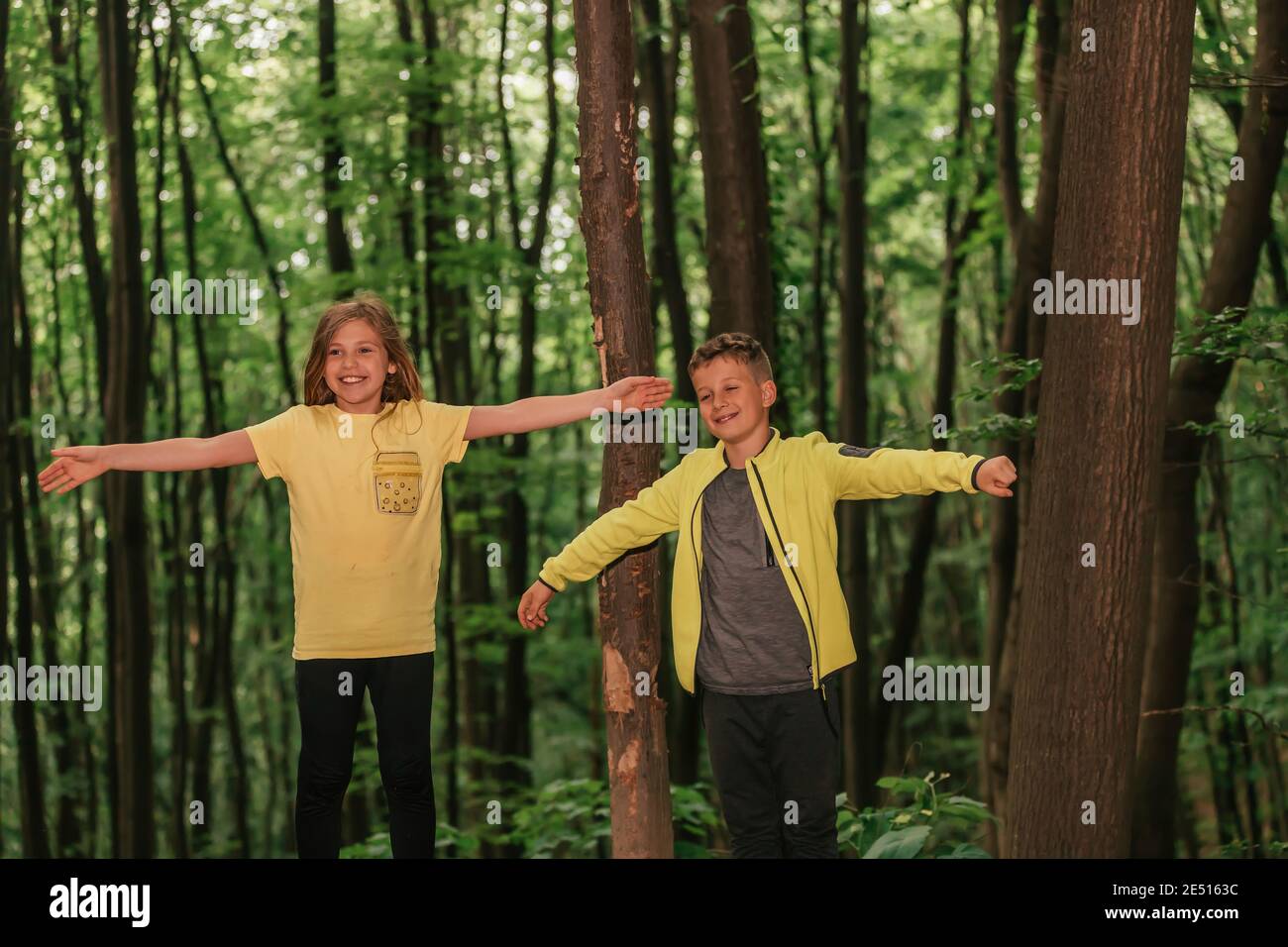 Godendo la natura beutiful. Felice ragazzino e ragazza con le braccia sollevate godendo l'aria fresca nella foresta verde. Messa a fuoco selettiva Foto Stock