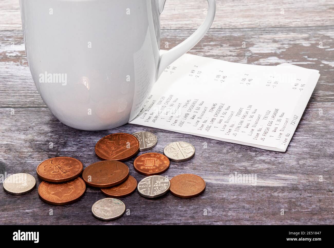 Una ricevuta di acquisto con alcune monete cambiare e una tazza Foto Stock