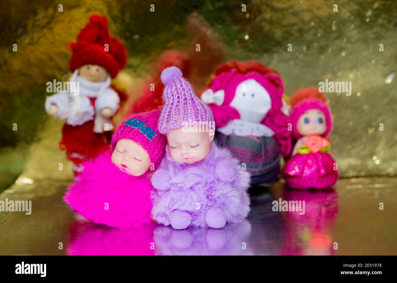 Due personaggi giocattolo di bambini piccoli in abiti caldi Rosa e rosso dormono. L'amore è scritto sul cappuccio. E giocattoli fatti a mano per bambini. Indietro d'oro Foto Stock
