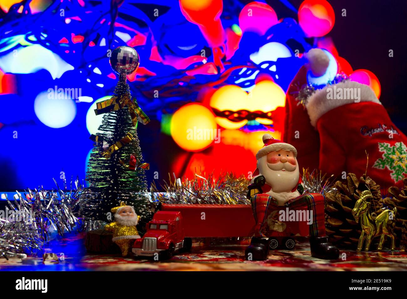 Big Babbo Natale è seduto su un camion rosso e in attesa del nuovo anno. Albero di Natale e accanto alla figura di Santa piccola. Coni di Natale Foto Stock