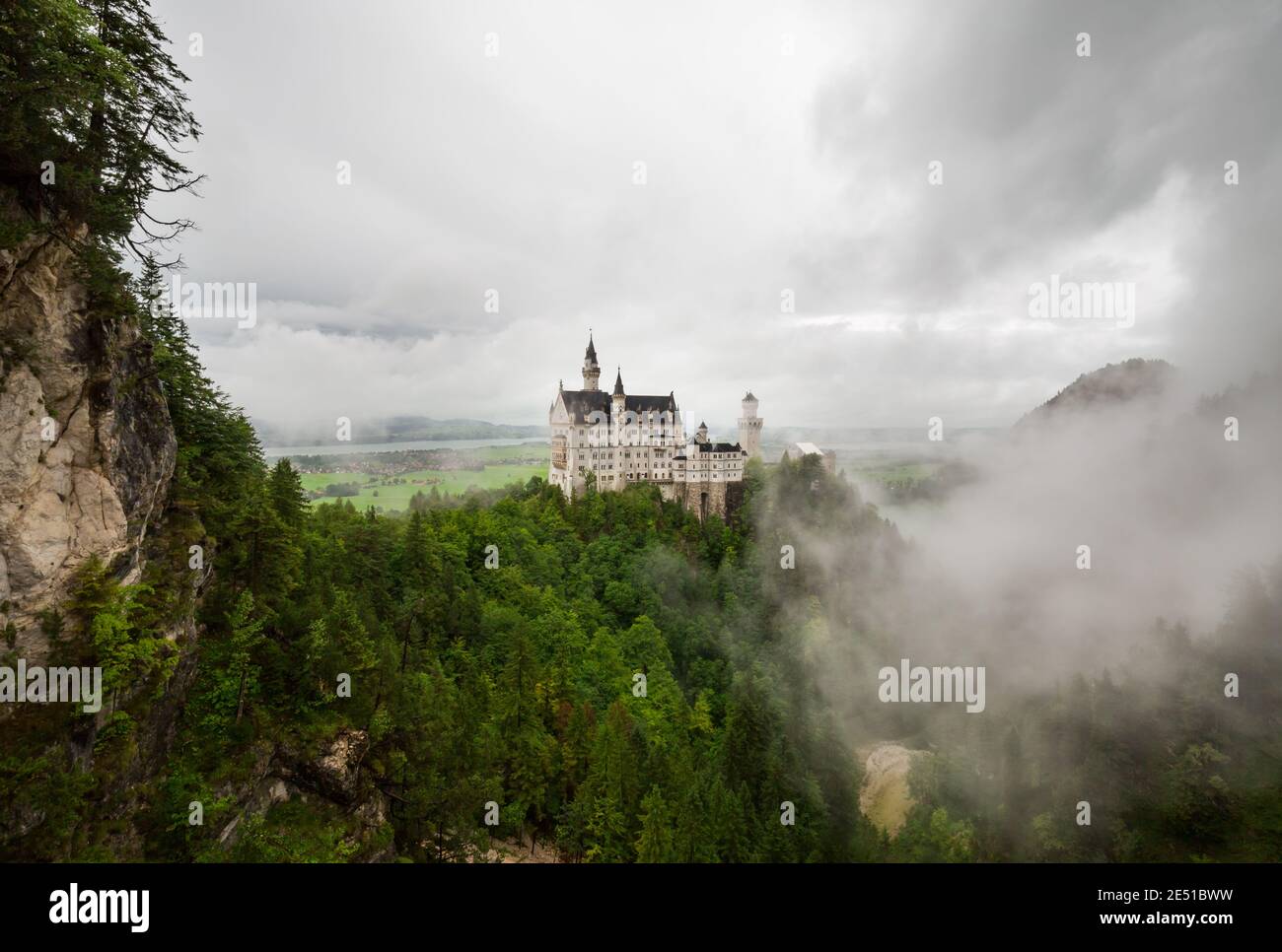 Ampio angolo di vista di un paesaggio tedesco con un antico castello circondato da basse nuvole, contro un cielo scuro nuvoloso Foto Stock