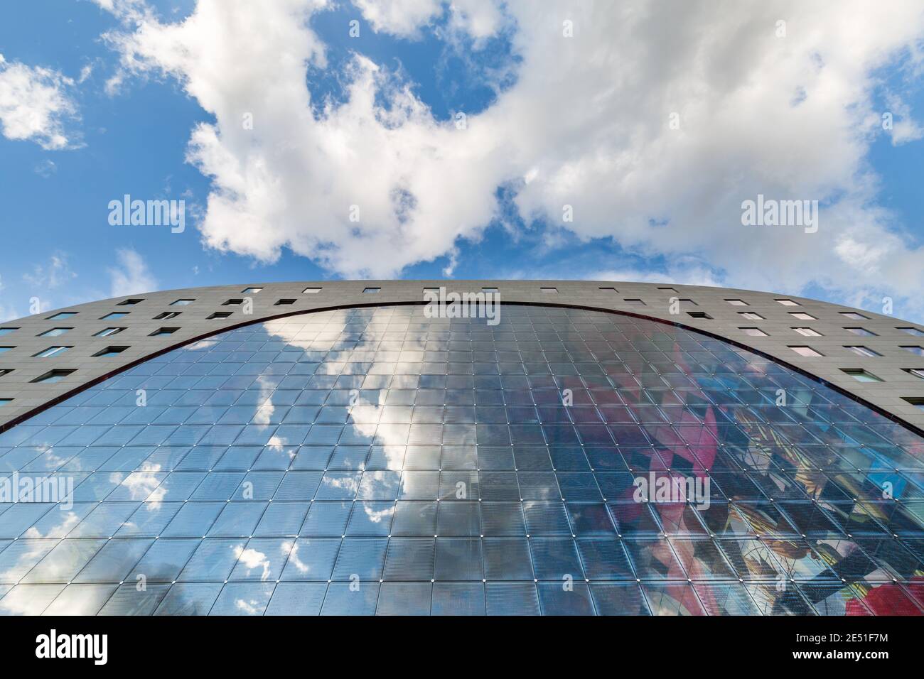 Vista grandangolare simmetrica di una moderna struttura in vetro riflettente il cielo estivo blu con nuvole soffici sopra Foto Stock