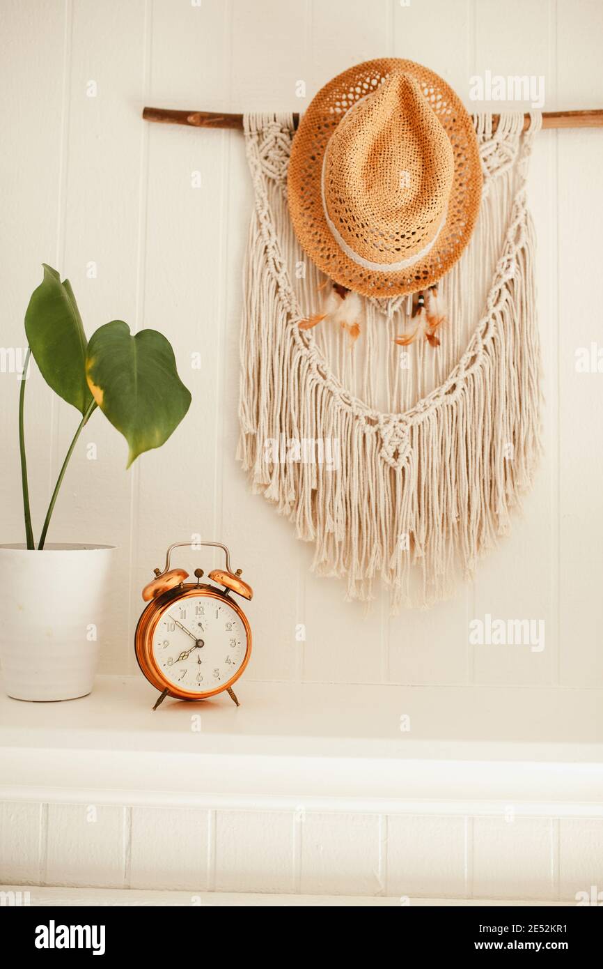 Camino in legno bianco con macrame e sogni catcher sulla parete, con piante casa e allarme rame vintage sulla mensola fuoco posto Foto Stock