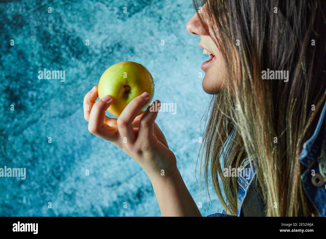 Donna che mangia mela su sfondo blu Foto Stock