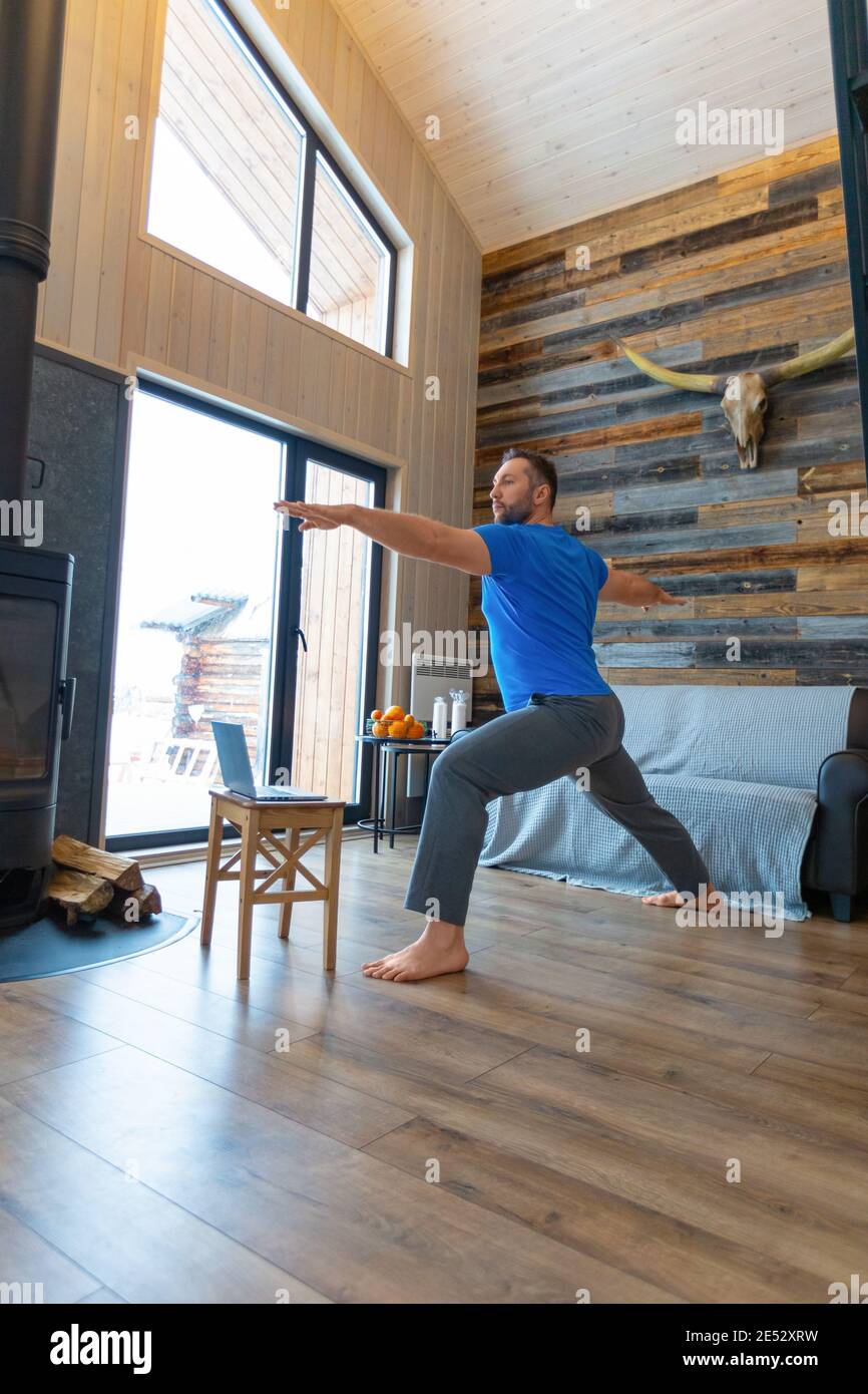 Un uomo lavora a casa online di fronte a un monitor portatile. Pilates, yoga e concetto di stile di vita sano. Foto verticale. Foto Stock