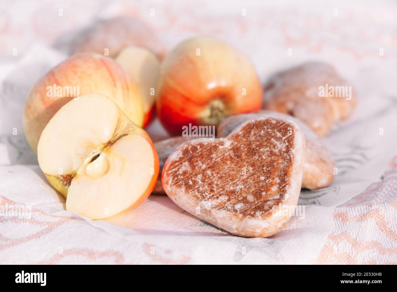 Biscotti di pan di zenzero smaltati a forma di cuore. Picnic in natura, spuntino leggero con mele e biscotti. Prodotti da forno per San Valentino. Messa a fuoco selettiva Foto Stock