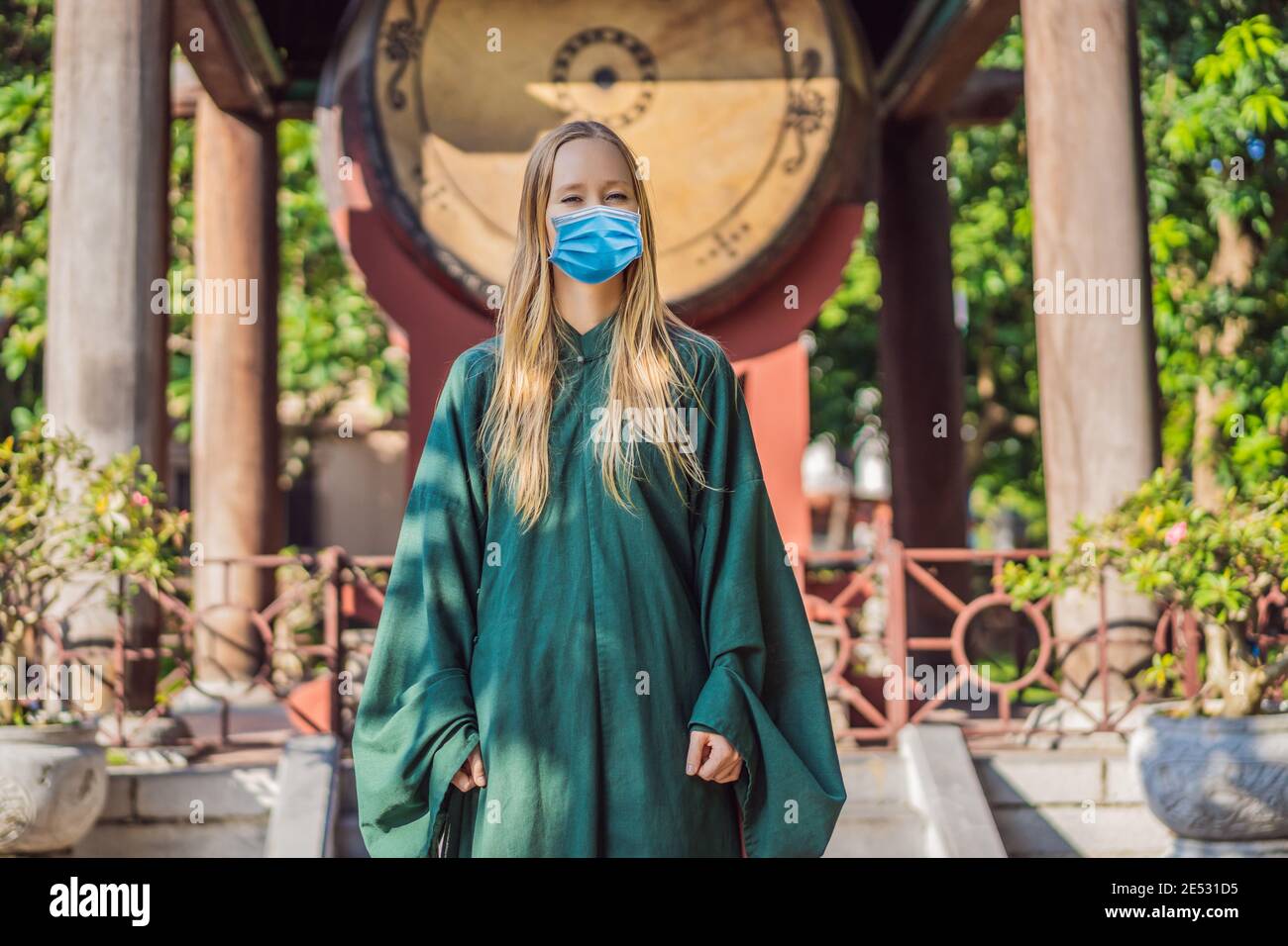 Donna turistica che indossa una maschera medica durante COVID-19 coronavirus in Nazionale vietnamita abito in Tempio della Letteratura in Hanoi in Sud-est asiatico Foto Stock