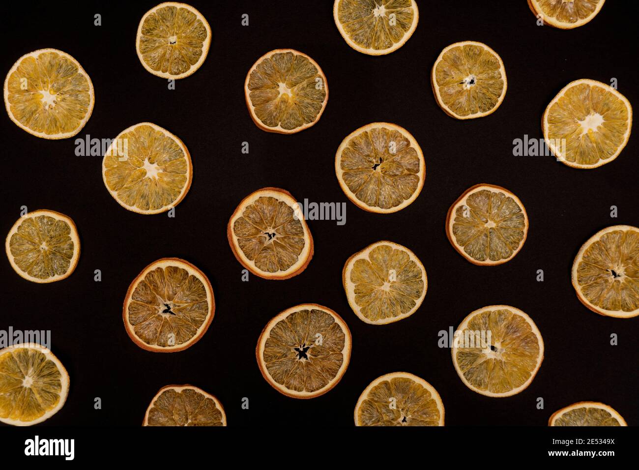 Modello ripetitivo di arance e tangerini essiccati su sfondo nero. Foto Stock