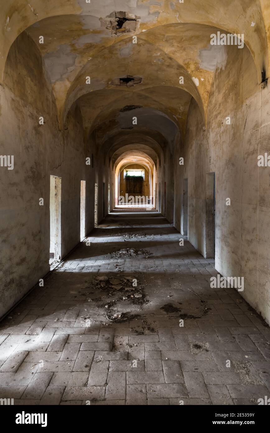 Vista grandangolare simmetrica di un corridoio in un antico Monastero abbandonato in Italia centrale Foto Stock