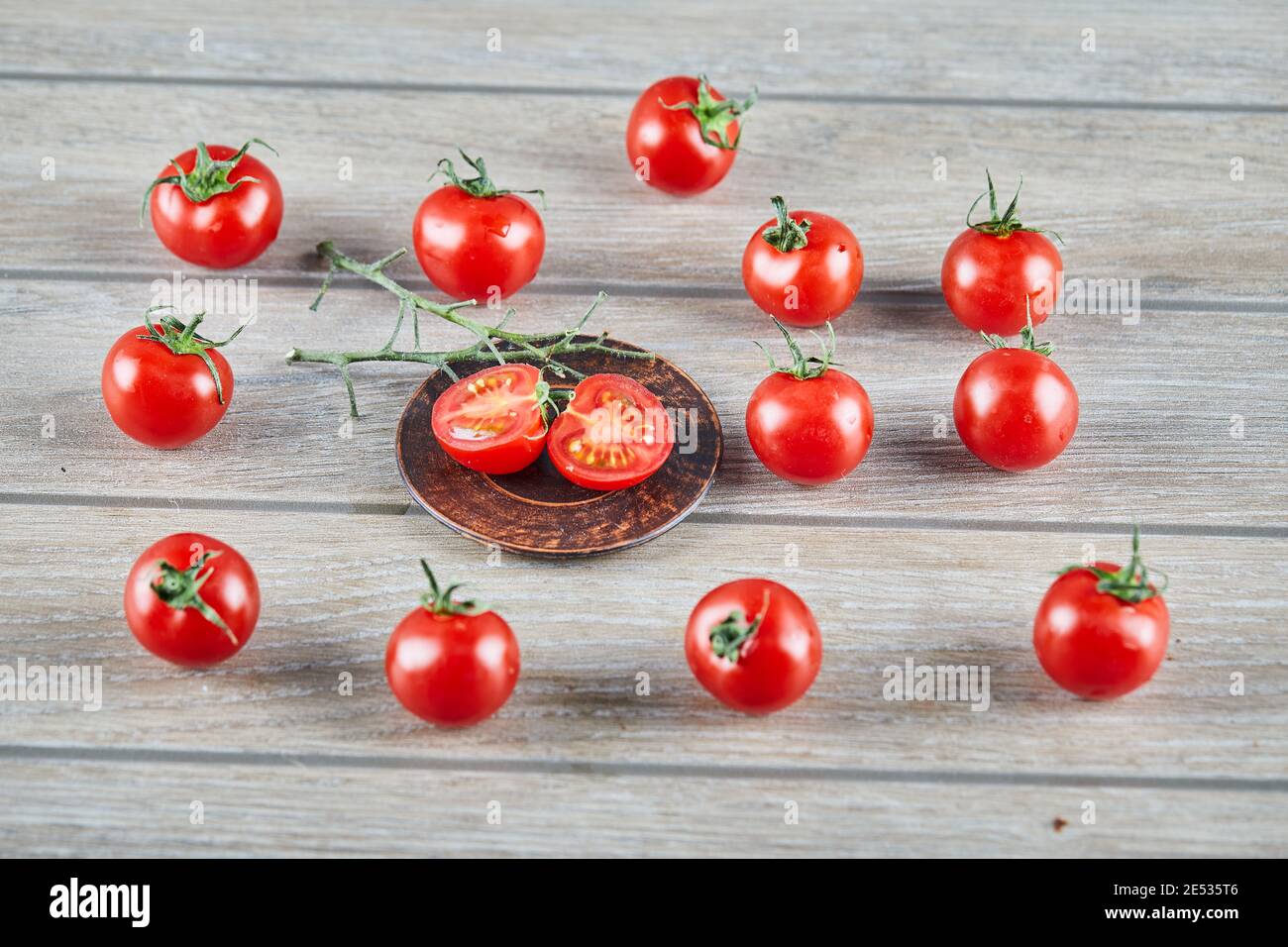 Mazzetto di pomodori freschi succosi e fette di pomodoro sopra tavolo di legno Foto Stock