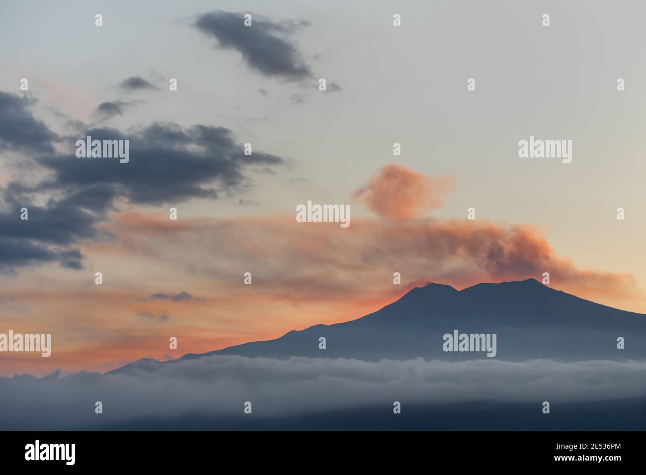 La cima del vulcano italiano Etna, circondata da nuvole soffici, al tramonto Foto Stock