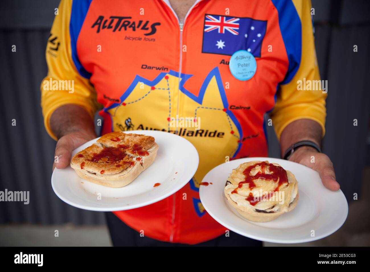 Il ciclista di AllTrails raccoglie un paio di torte di carne da una panetteria. Foto Stock